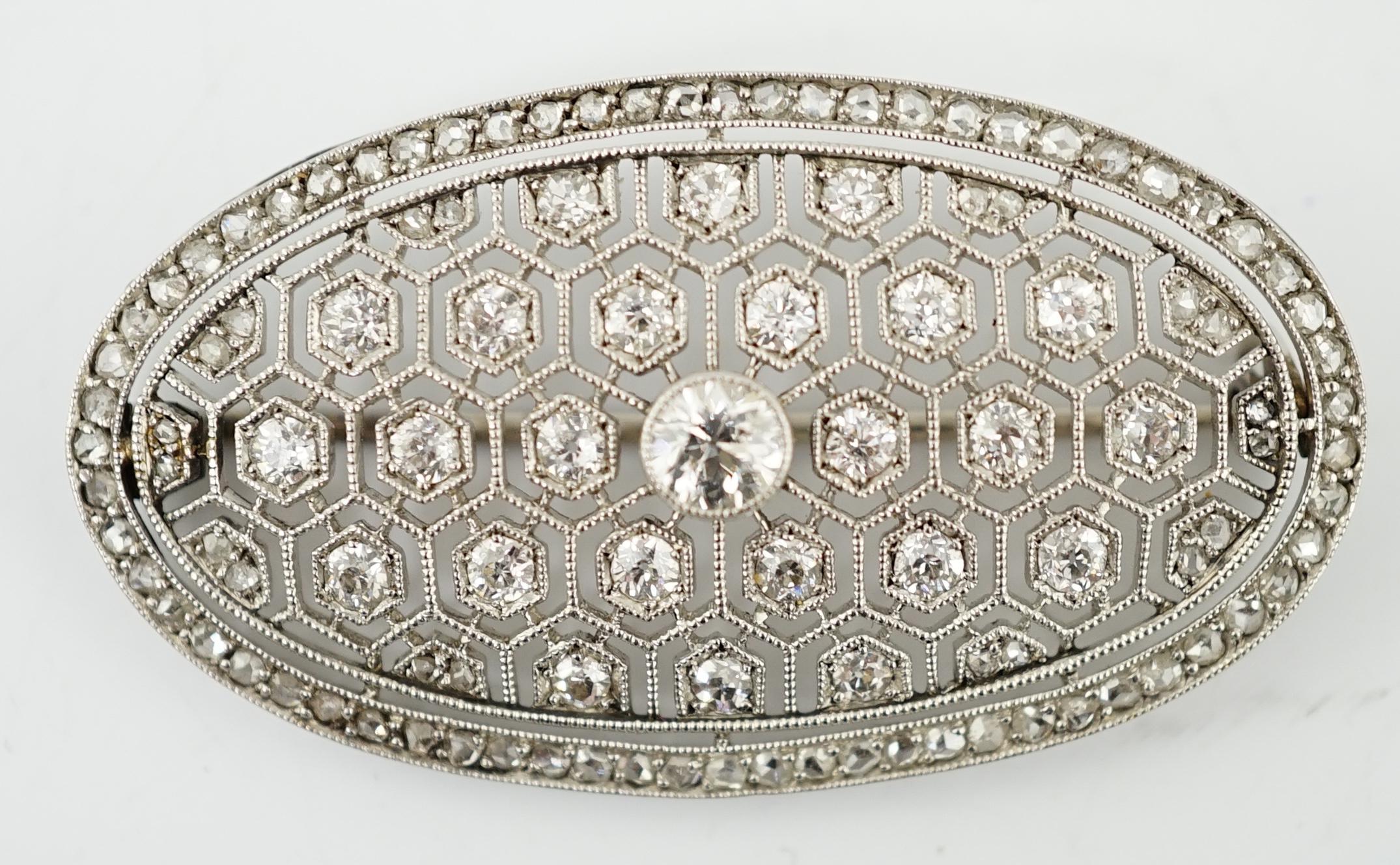 A Belle Epoque platinum and millegrain diamond cluster set oval brooch